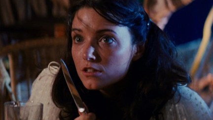 Young Marion (Karen Allen) peers at the viewer wide eyed while holding a knife